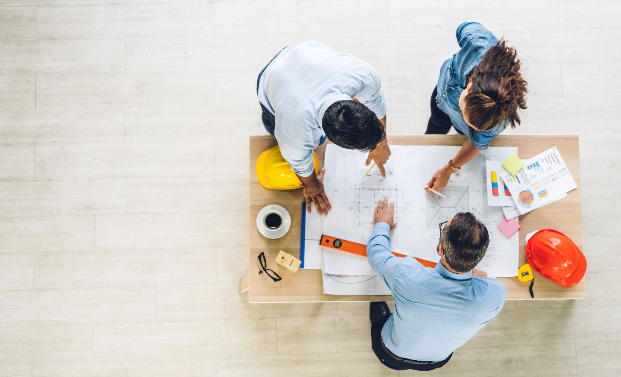 Professional of team architect industrial engineer cargo foreman in helmet working new construction project architectural plan with blueprint and construction tool on table at the building site